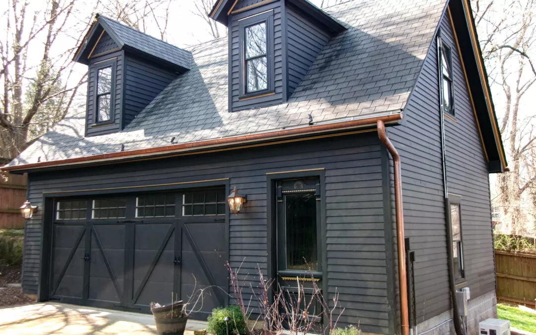 Miller's Guttering Munfordville, KY A modern house with dark gray siding and new gutters, featuring a large, three-car garage and multiple windows, surrounded by trees.