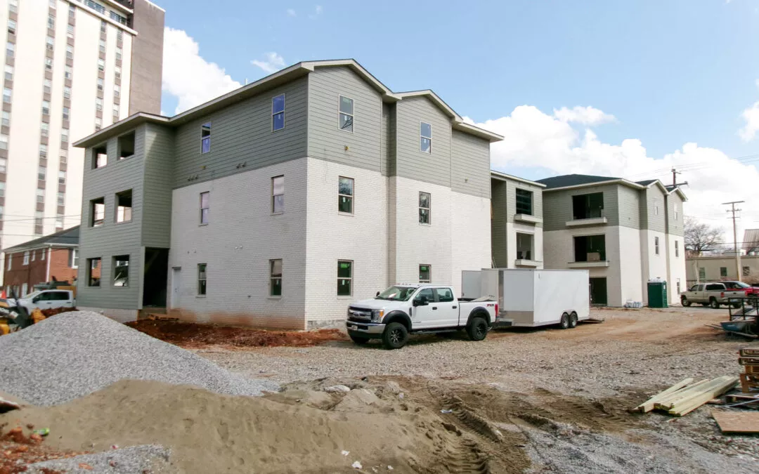 Miller's Guttering Munfordville, KY Newly constructed multi-unit residential building with new gutters, unpaved surroundings and construction materials, featuring parked vehicles and clear skies.
