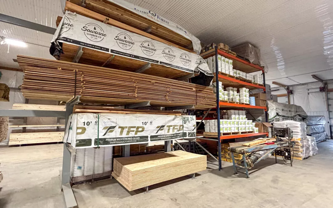 Martin's Truss Manufacturing Elkhart IN Interior of a warehouse with neatly organized building supplies including stacks of wood, bundles of insulation, and shelving with various construction materials.