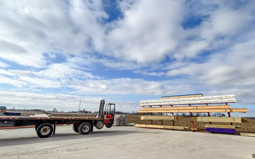 Martin's Truss Manufacturing Elkhart IN A forklift moves lumber on a construction supply yard under a cloudy sky, with a flatbed trailer in the foreground.