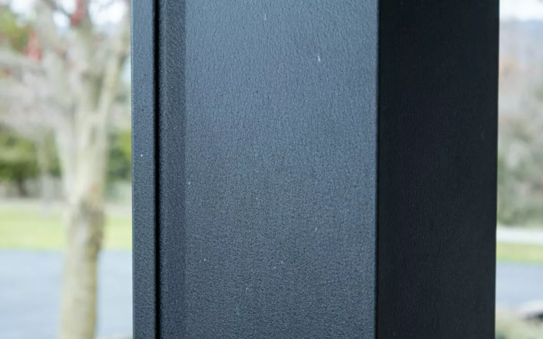 Martin's Trim Forming Millmont, PA Close-up image of a gray, textured metal surface with an out-of-focus background that includes a tree and some greenery.