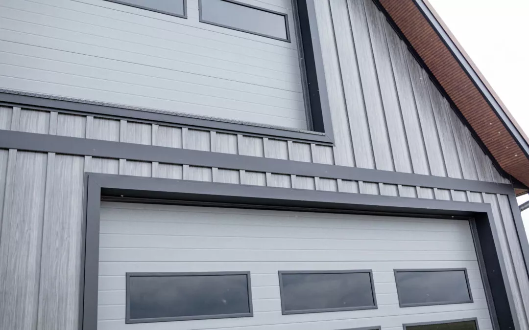 Martin's Trim Forming Millmont, PA Close-up of a modern building with vertical gray siding and large garage doors with rectangular windows. The upper portion also features horizontal trim and narrow windows.