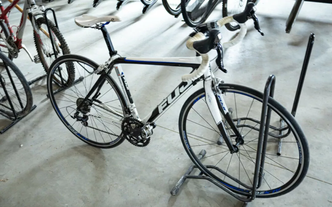 H & H Bicycles Liberty Kentucky A white and black road bike with blue accents is parked in a bike rack among other bicycles in a bike shop