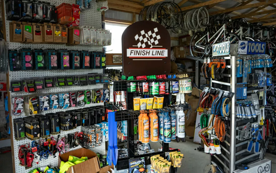H & H Bicycles Liberty Kentucky A bike shop interior displaying various cycling accessories including lubricants, tires, tubes, tools, and other biking gear organized on shelves and racks.