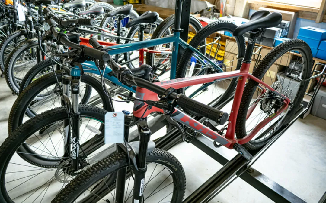 H & H Bicycles Liberty Kentucky Several bicycles are parked in a bike shop, including a red and a blue bike in the foreground. The space is filled with various bike models lined up in rows.