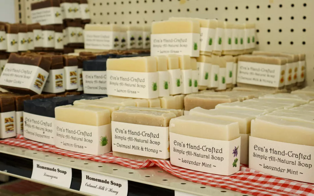 Lakeside Country Store Mishicot, Wisconsin A display of stacked handmade soaps in various scents, including oatmeal milk & honey and lavender mint, arranged on shelves with labels reading "Eva's Hand-Crafted all-natural soap.