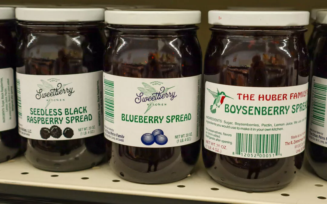 Lakeside Country Store Mishicot, Wisconsin Three jars of fruit spreads on a store shelf: seedless black raspberry, blueberry, and boysenberry. Each jar has a distinct label and brand name.