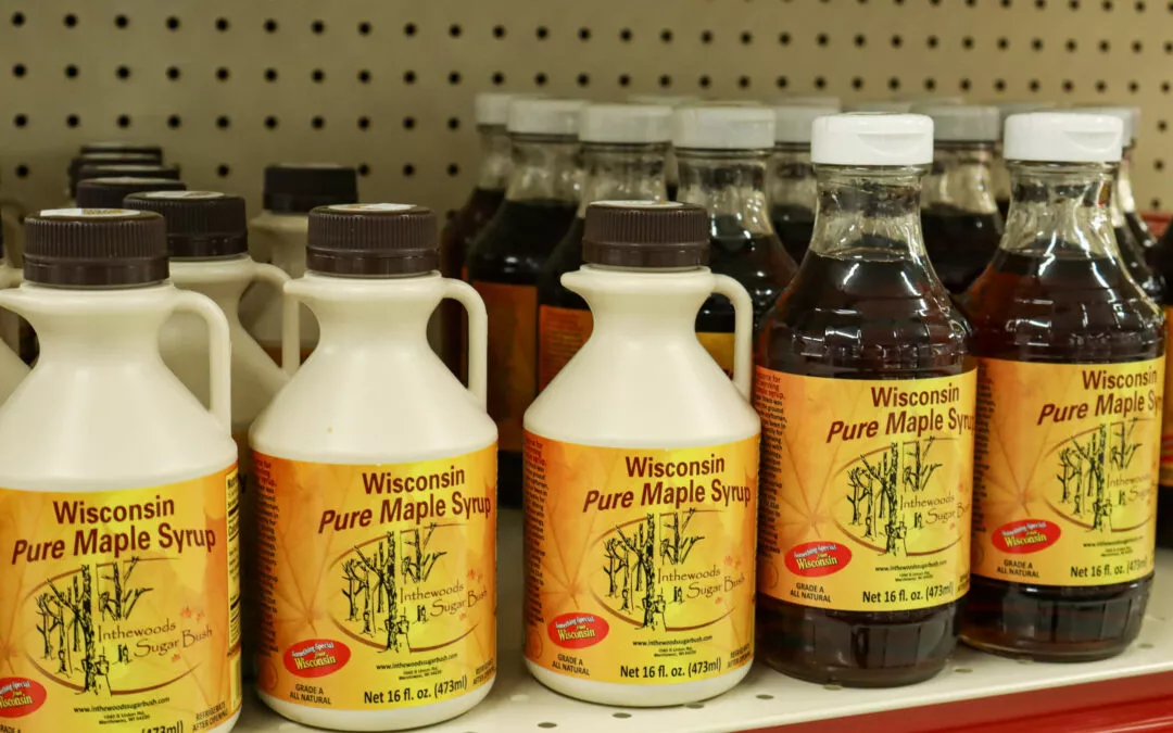 Lakeside Country Store Mishicot, Wisconsin Bottles of Wisconsin Pure Maple Syrup are displayed on a store shelf, with the front row showing both jug and bottle packaging.