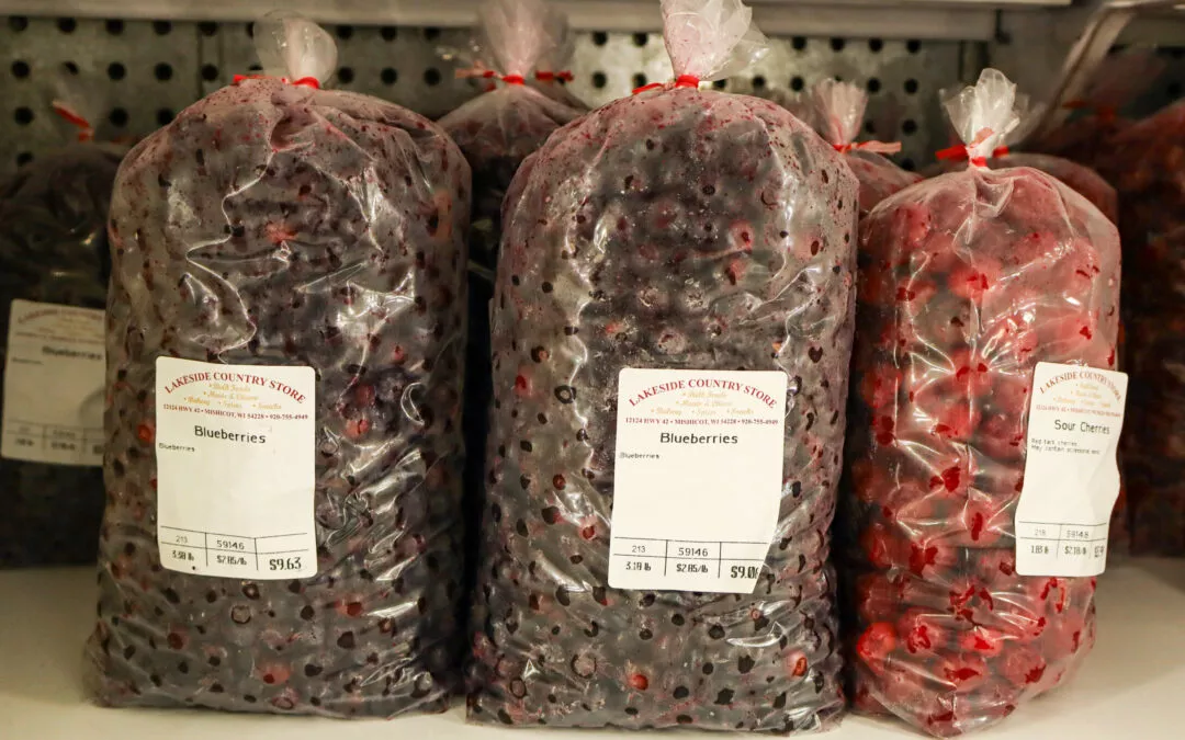 Lakeside Country Store Mishicot, Wisconsin Three large plastic bags filled with frozen blueberries are displayed on a shelf. They are labeled "Amish Country Store" with pricing and weight information.