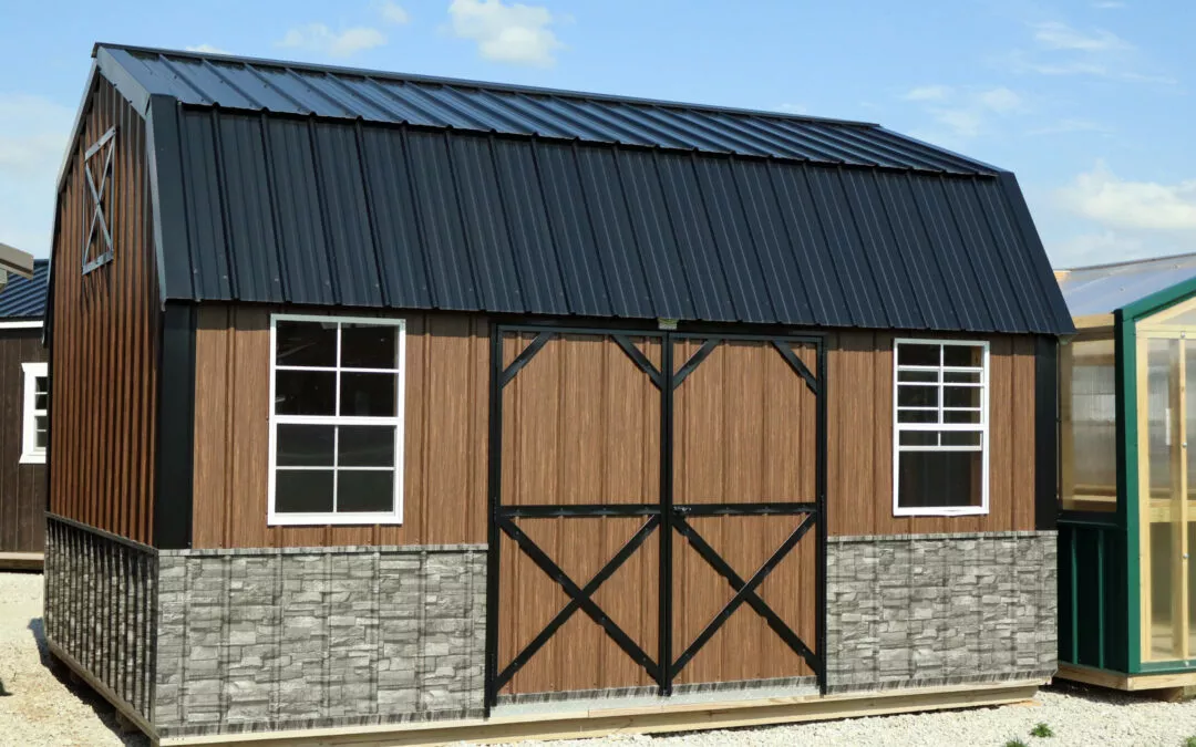 Cedar Ridge Sales Ramsey IL Ava IL A brown and black storage shed with two windows and large barn-style double doors, placed on a gravel surface next to a greenhouse.