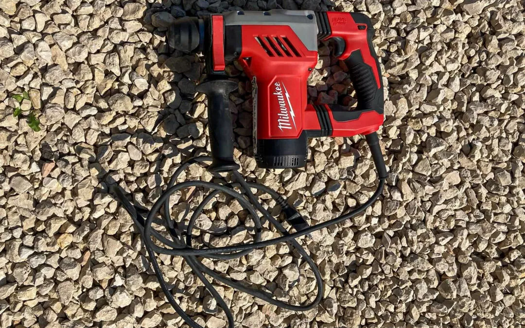 Southland Rentals Altona Canada A red and black Milwaukee power drill with a cord and handle lies on a gravel surface.