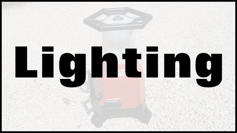 A red and black portable work light on gravel, with the word "Lighting" in large black letters overlaying the image.