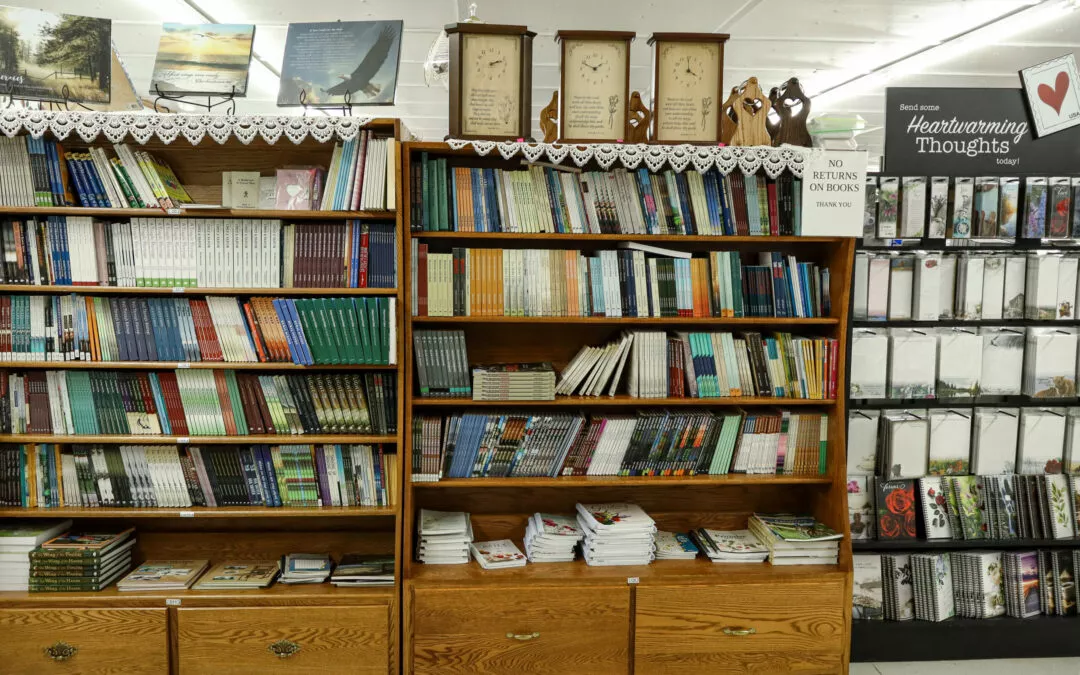 Brubaker's Sewing & Furniture Withee, WI A bookstore's shelves filled with various books and a card display section labeled "Heartwarming Thoughts" on the right. A sign on the middle shelf reads "No Returns on Books.