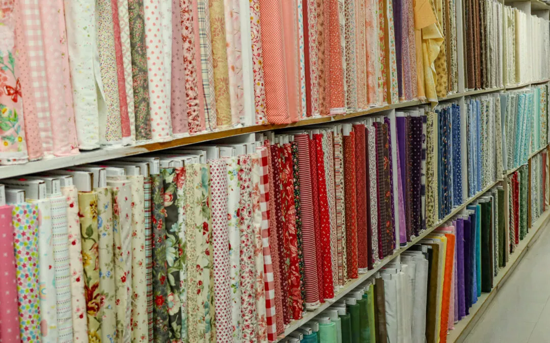 Brubaker's Sewing & Furniture Withee, WI A wall of neatly rolled fabric bolts in various colors and patterns in a store.
