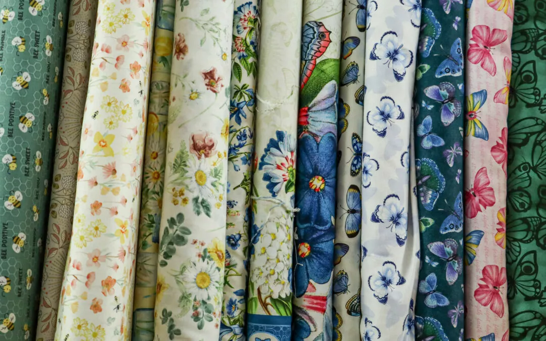 Brubaker's Sewing & Furniture Withee, WI Rolls of fabric with various floral patterns and colors are displayed vertically in a row.