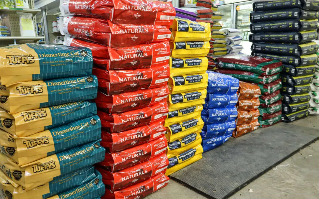 Chippewa Vallaey Dairy Supply Stanley, WI Stacks of colorful pet food bags are neatly arranged on the floor of a store.