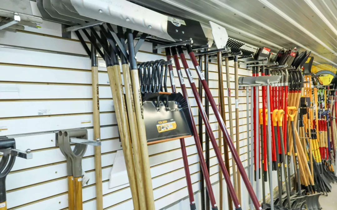 Chippewa Vallaey Dairy Supply Stanley, WI Various gardening tools, including shovels, rakes, and spades, are hanging on display hooks in a store.