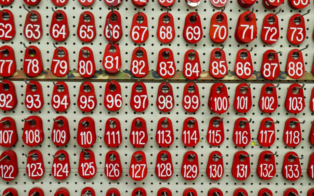 Chippewa Vallaey Dairy Supply Stanley, WI A wall with rows of red numbered key tags ranging from 1 to 180, hanging on hooks.