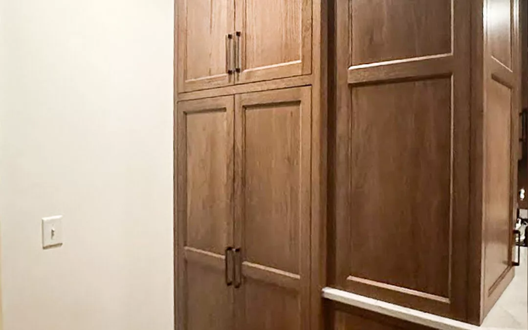 The Woodpecker Sullivan, Illinois Wooden kitchen cabinets with paneled doors and dark handles, adjacent to a white wall with a light switch.