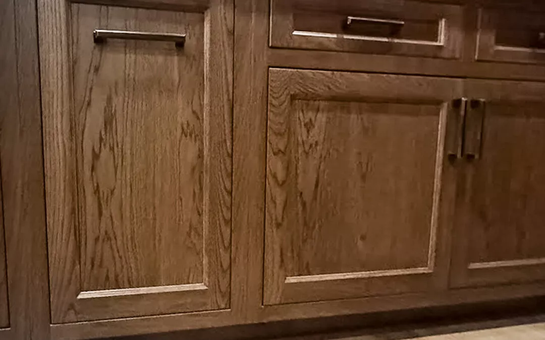 The Woodpecker Sullivan, Illinois Wooden kitchen cabinets with metal handles, featuring a natural wood grain pattern, set against a light-colored floor.