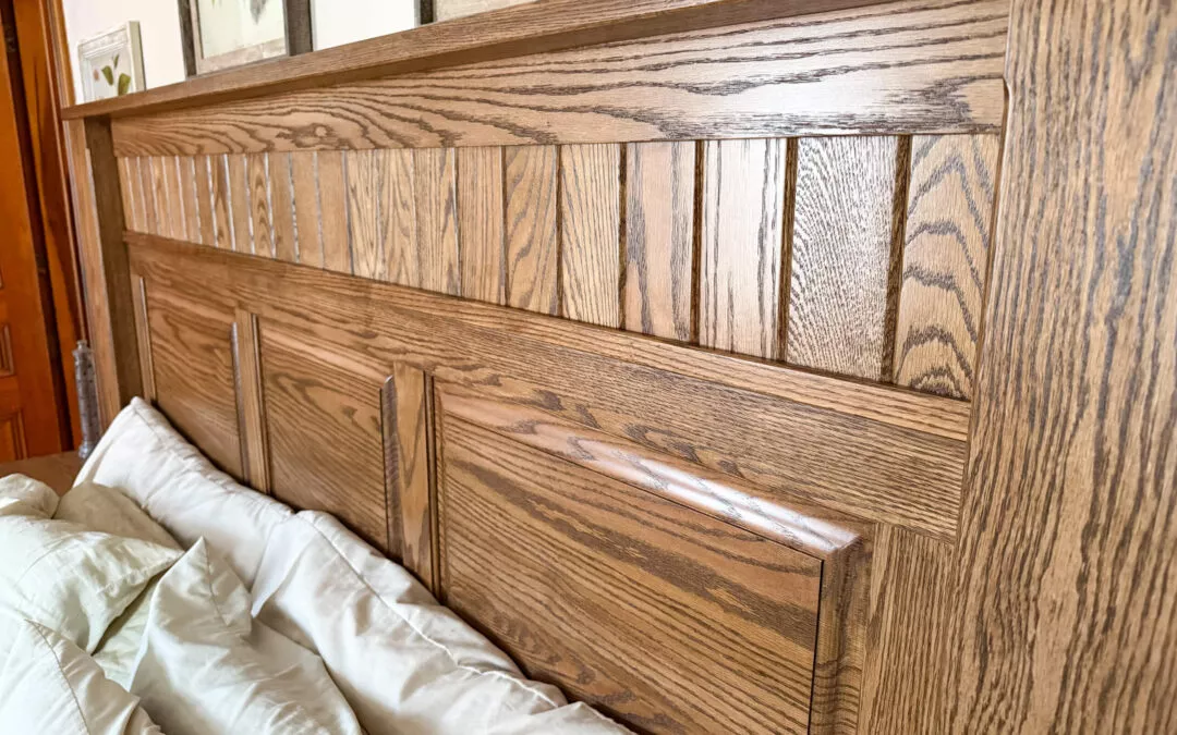 Sugar Valley Chair Shop Loganton, PA Wooden headboard with a geometric pattern is attached to a bed with light green bedding. Framed artwork is visible above the headboard on a white wall.