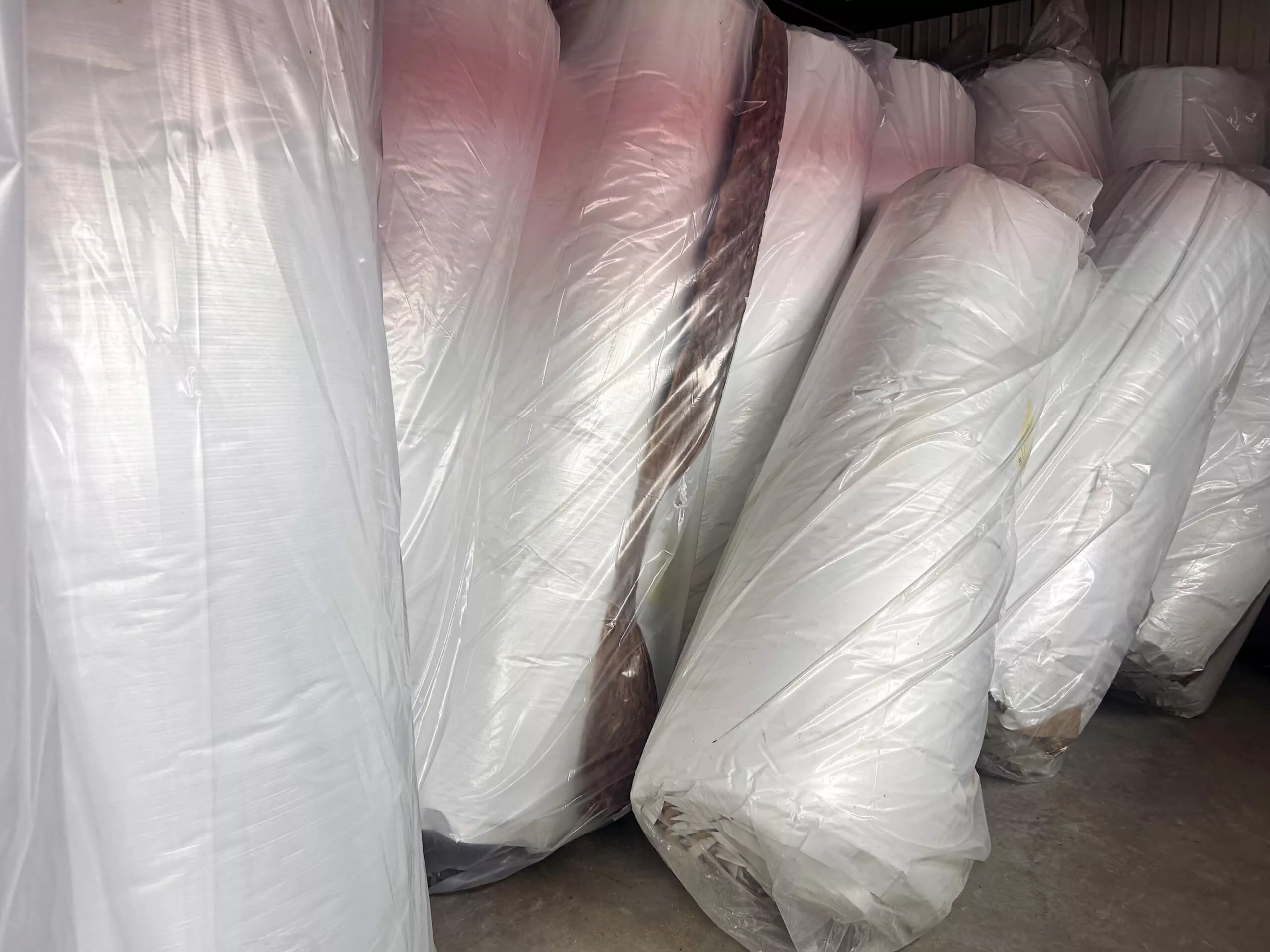Amish Ridge Metals Perry, OH Large rolls of white material wrapped in plastic are stored upright in a warehouse or storage area.