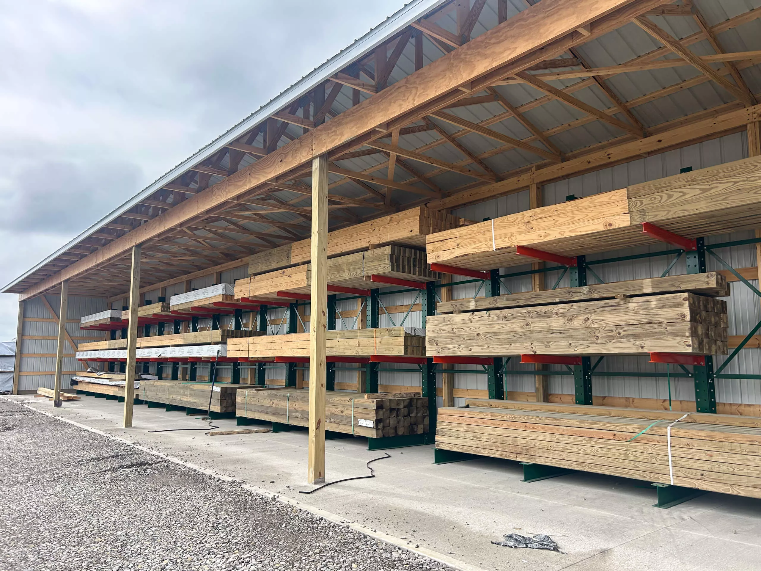 Amish Ridge Metals Perry, OH Stacks of lumber neatly organized on metal shelves under a large open-sided shed at a lumber yard.