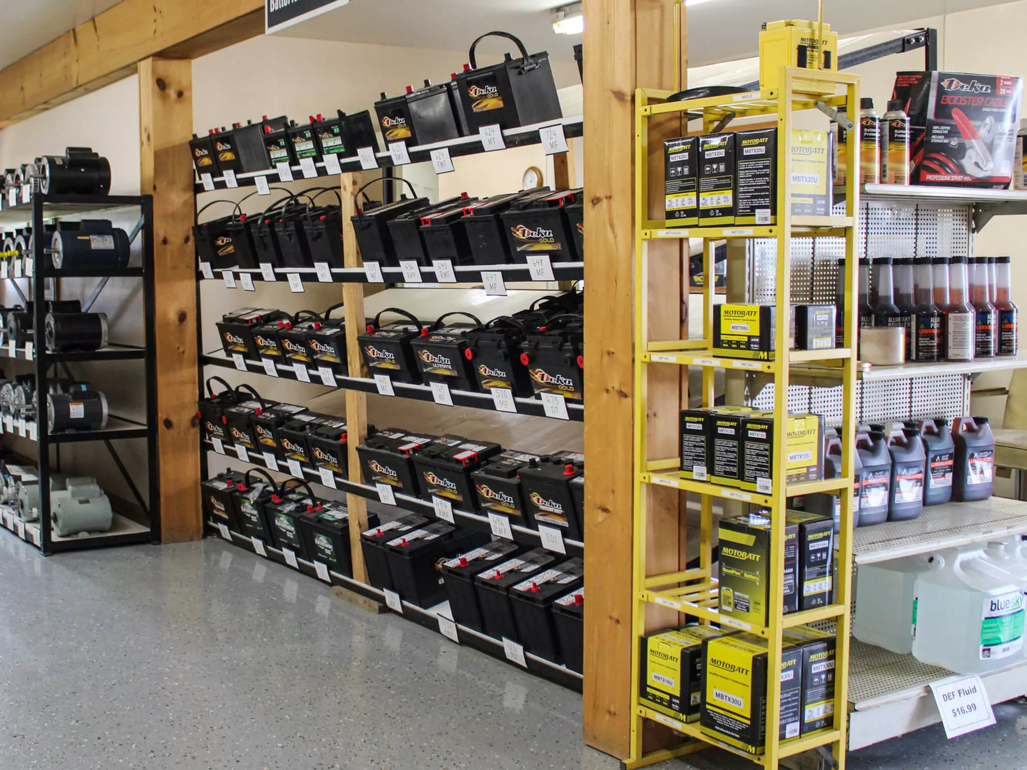 Shelves stocked with automotive batteries, oil containers, and other car maintenance supplies in a store.