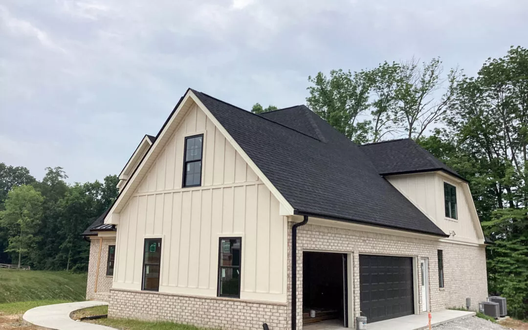 Miller's Guttering Seamless Gutters Arthur, IL New two-story house with light-colored brick and vertical siding, dark roof, attached garage, and unfinished landscaping under a cloudy sky.