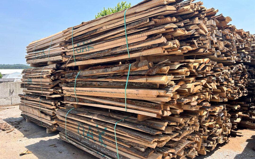 Leinbach's Sawmill Lumber Lancaster, PA Stacks of rough-cut wooden planks bound with green straps are piled outdoors in a lumber yard under a clear sky.