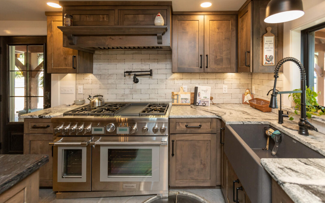 Stoney Lane Woodworking Custom Cabinetry Custom Kitchens Lancaster, PA Modern kitchen with wood cabinets, stainless steel gas range, double oven, farmhouse sink, marble countertops, and subway tile backsplash under warm lighting.