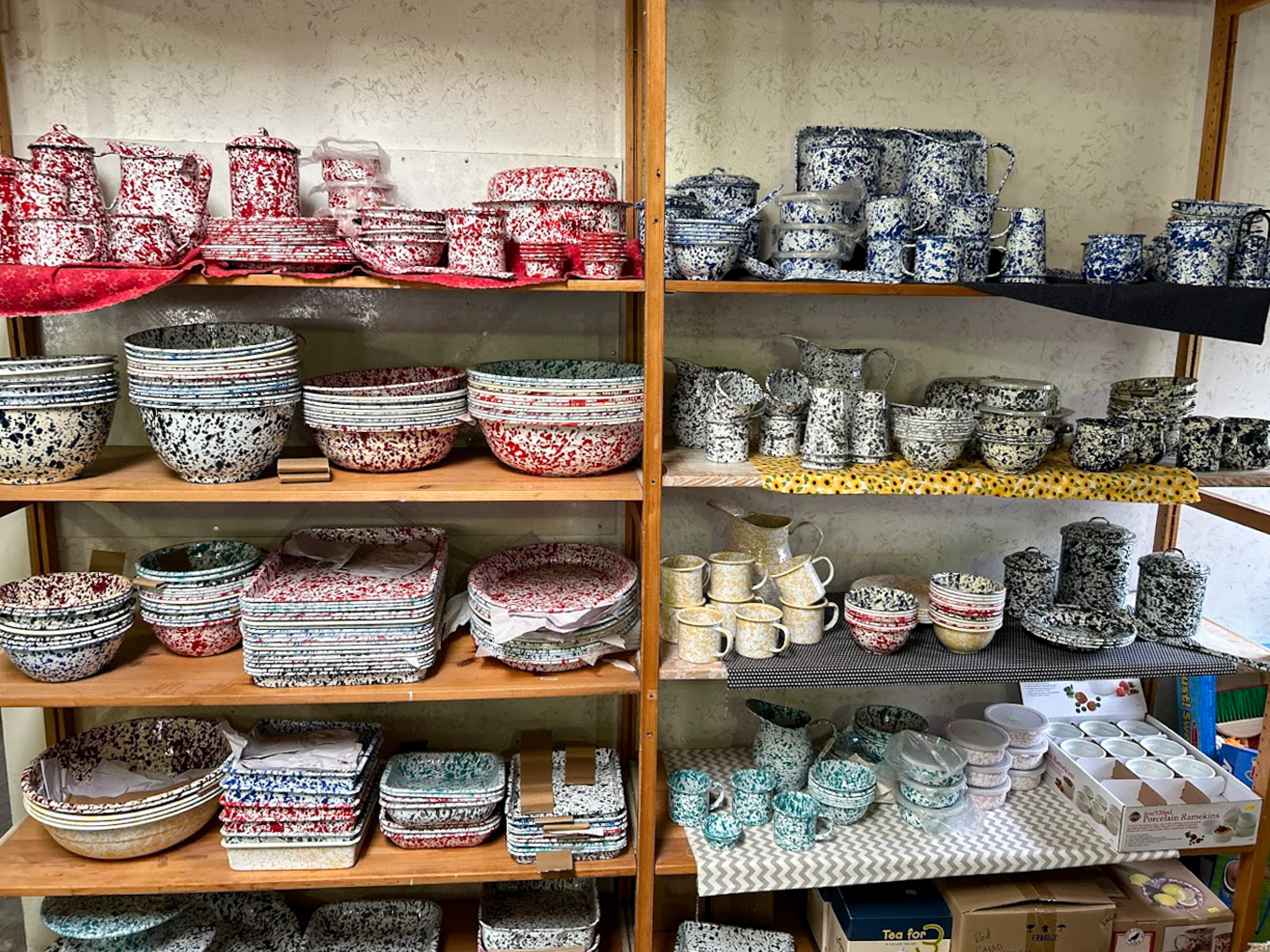 Country Variety Store Bellafontaine OH Shelves display colorful speckled ceramic dishware, including bowls, plates, mugs, and teapots in red, blue, black, and yellow patterns.