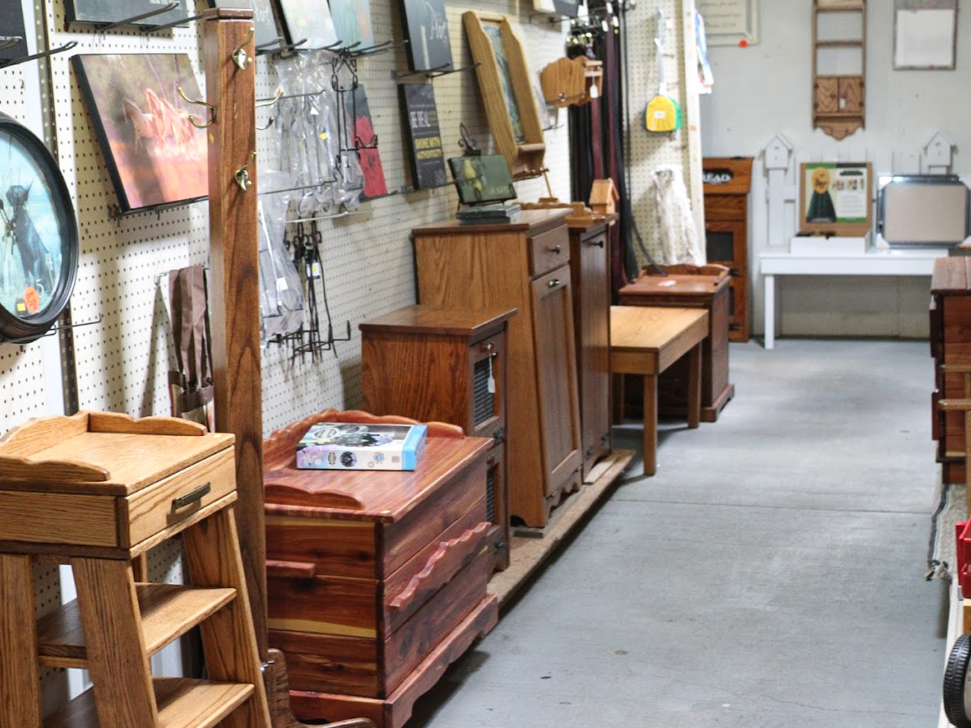 Country Variety Store Bellafontaine OH A row of wooden furniture pieces and assorted household items displayed along shelves and a wall inside a thrift store or resale shop.