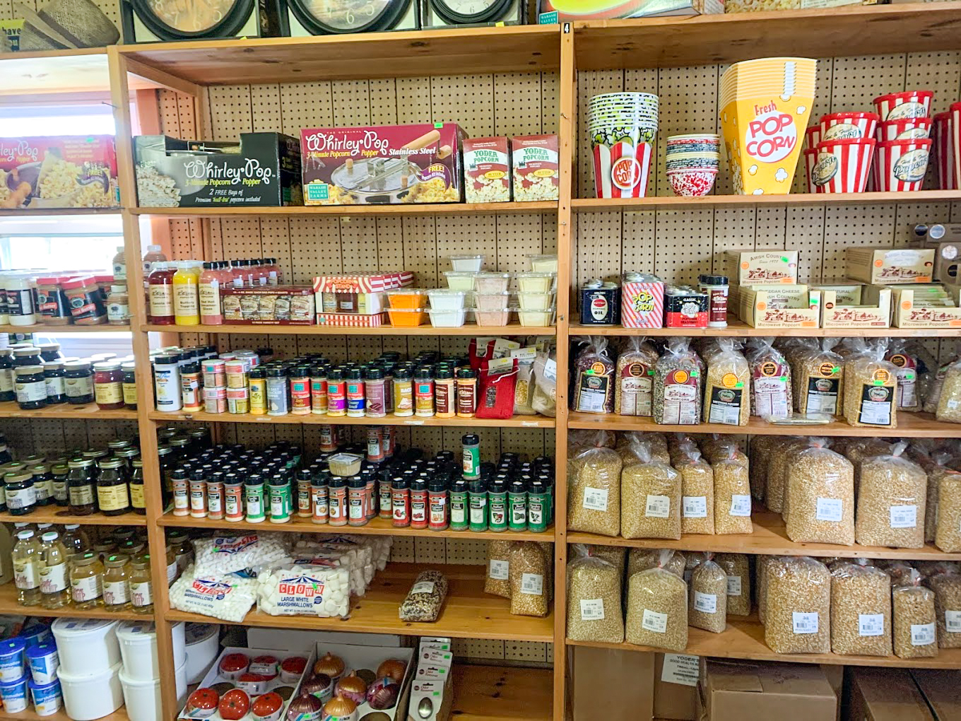 Country Variety Store Bellafontaine OH Wooden shelves stocked with popcorn supplies, seasonings, popcorn kernels, jars of preserves, and various condiment containers in a store.