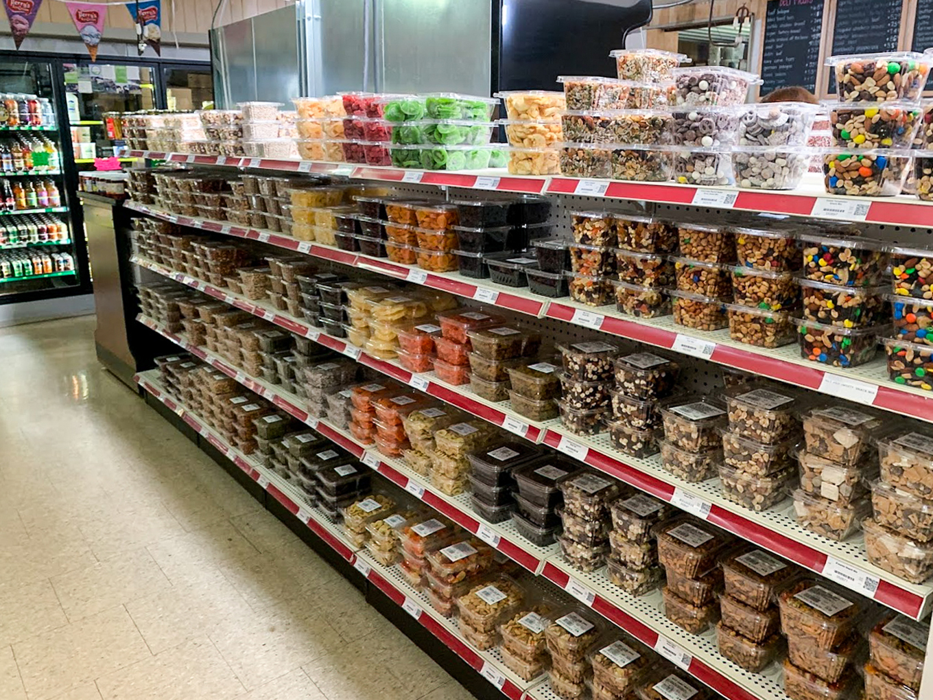 Country Variety Store Bellafontaine OH Shelves in a store display rows of clear plastic containers filled with various candies, nuts, and snacks, all labeled and arranged by type.
