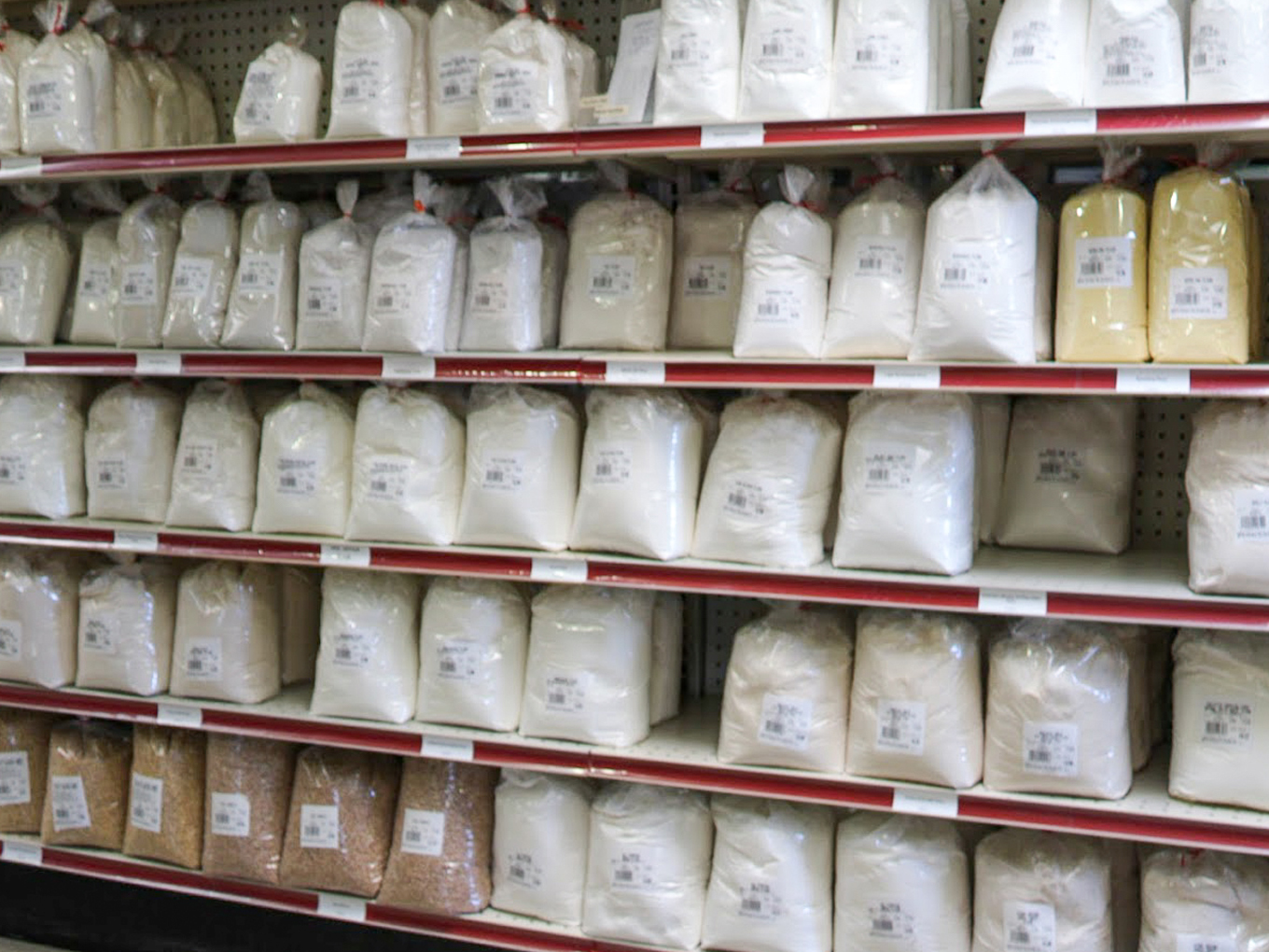 Country Variety Store Bellafontaine OH Shelves stocked with various types of flours and grains in clear plastic bags with labels at a grocery or bulk food store.