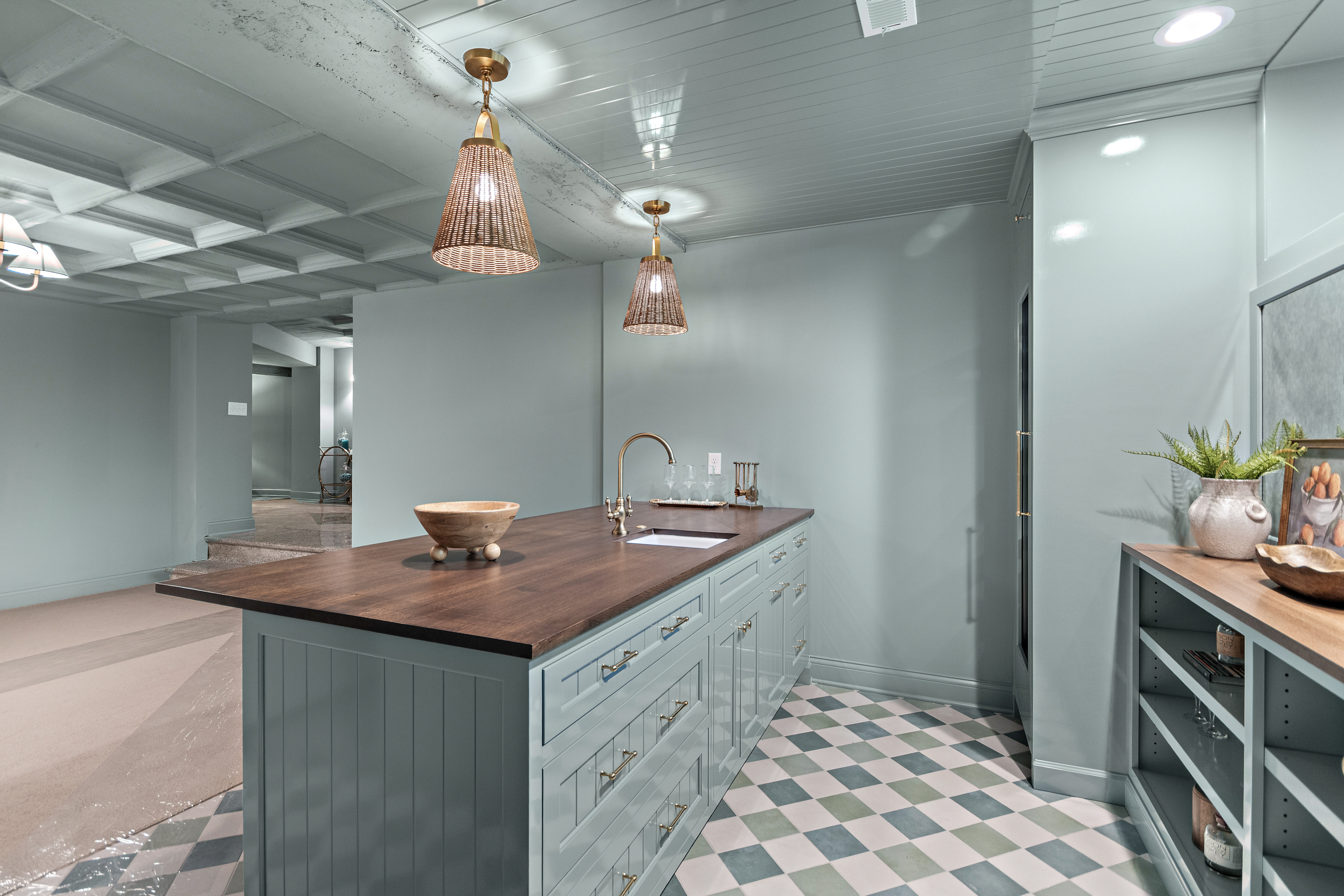 Kenrose Kitchen Kabinets Cabinetry Arthur IL A modern kitchen with light blue cabinets, a dark wood countertop, two pendant lights, checkered tile floor, and various kitchen items on the counter and shelves.