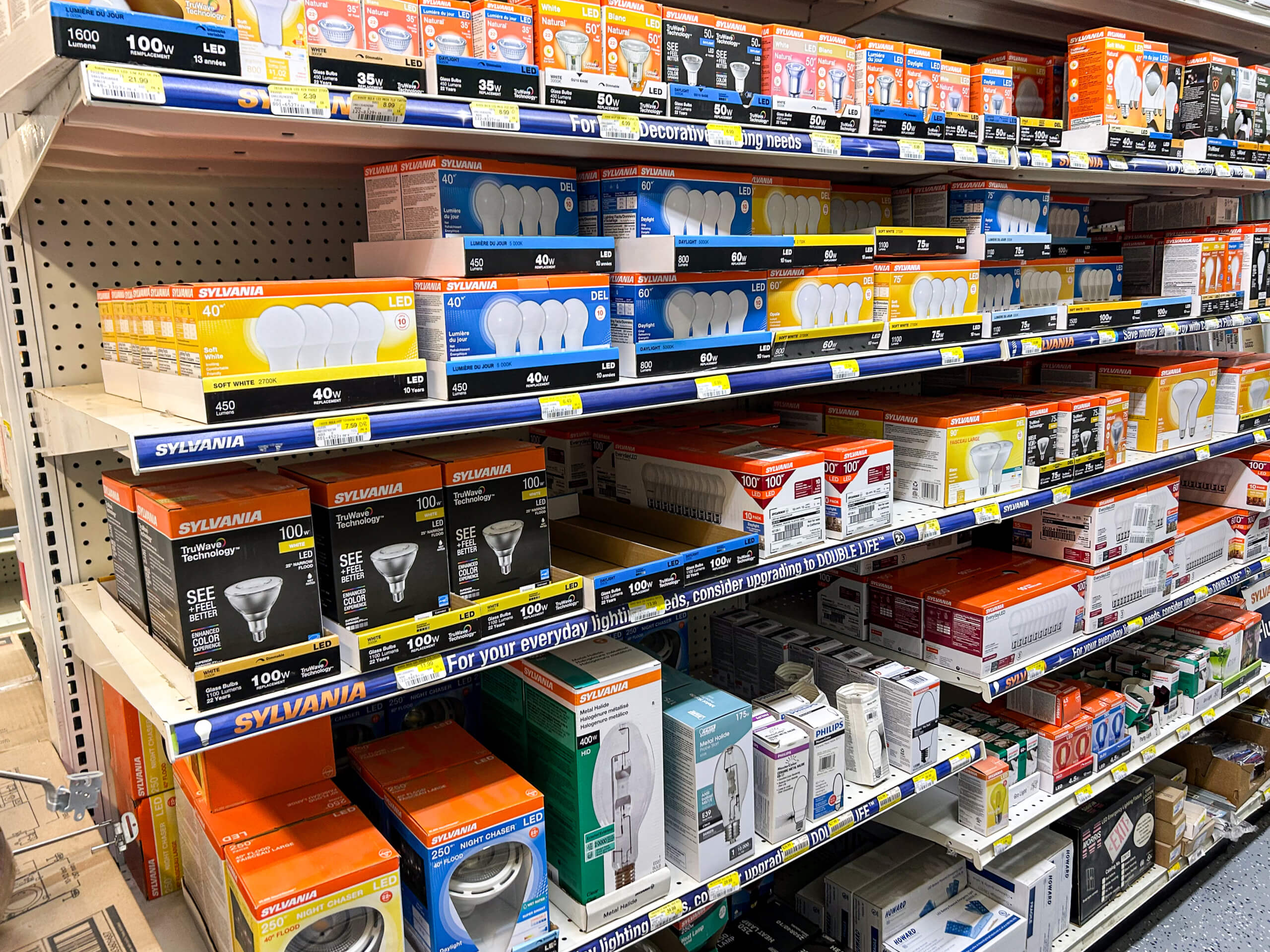 Benny's Hardware Barnett MO Store shelves stocked with various brands and types of light bulbs in colorful packaging, organized by wattage and style.