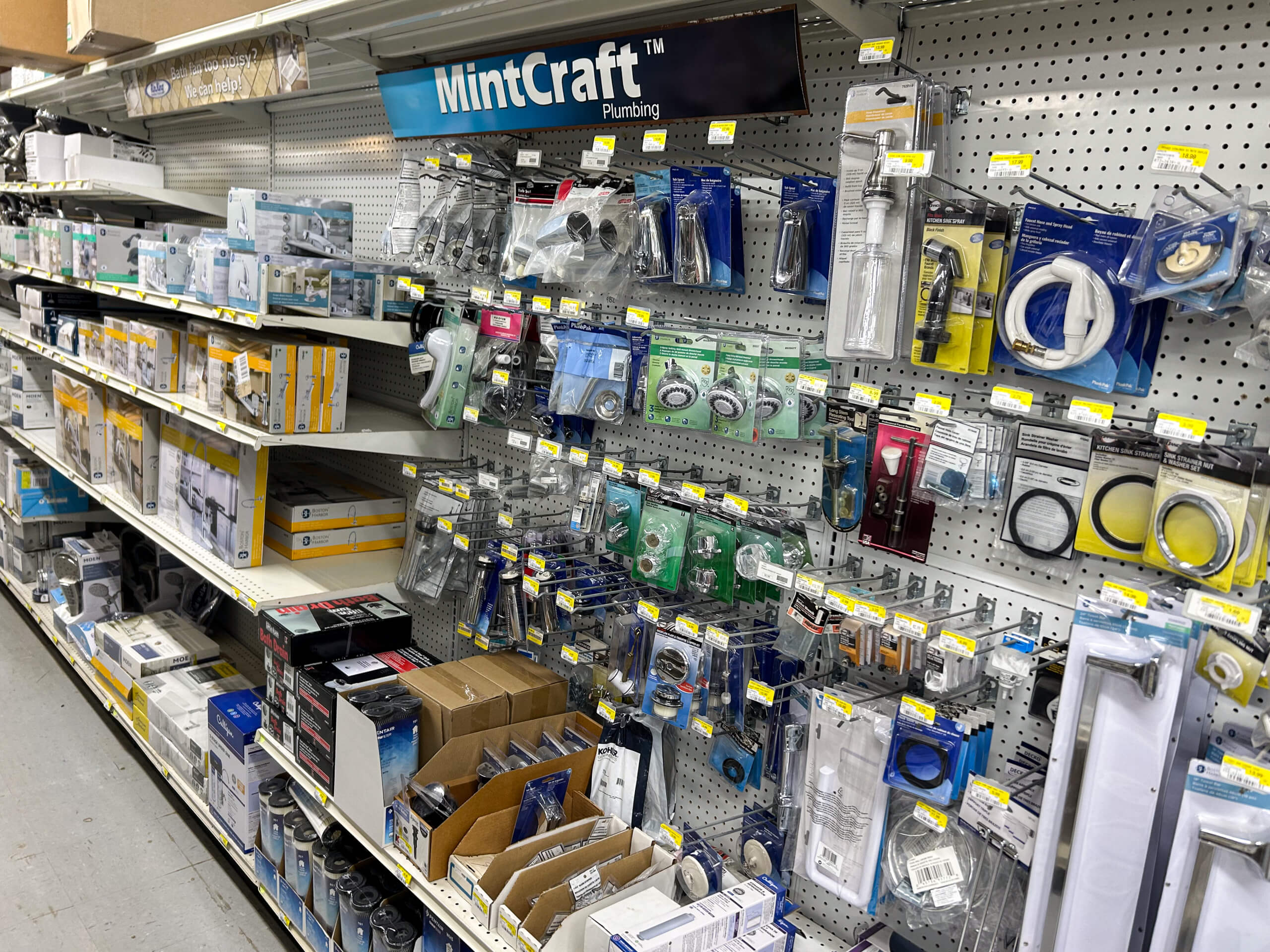 Benny's Hardware Barnett MO Store aisle with assorted MintCraft plumbing supplies and hardware items on display, including faucets, hoses, washers, and boxed products on metal shelves.
