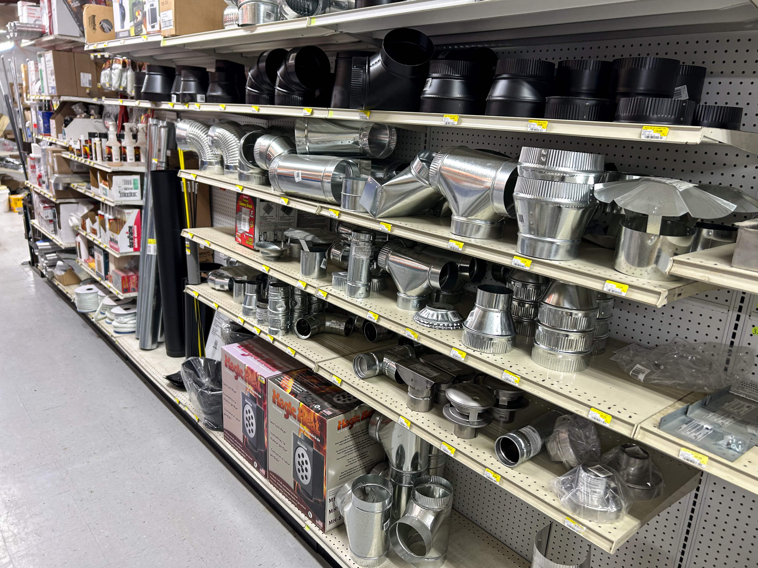 Benny's Hardware Barnett MO Shelves in a hardware store display various metal duct fittings, connectors, and vent parts organized by type and size.