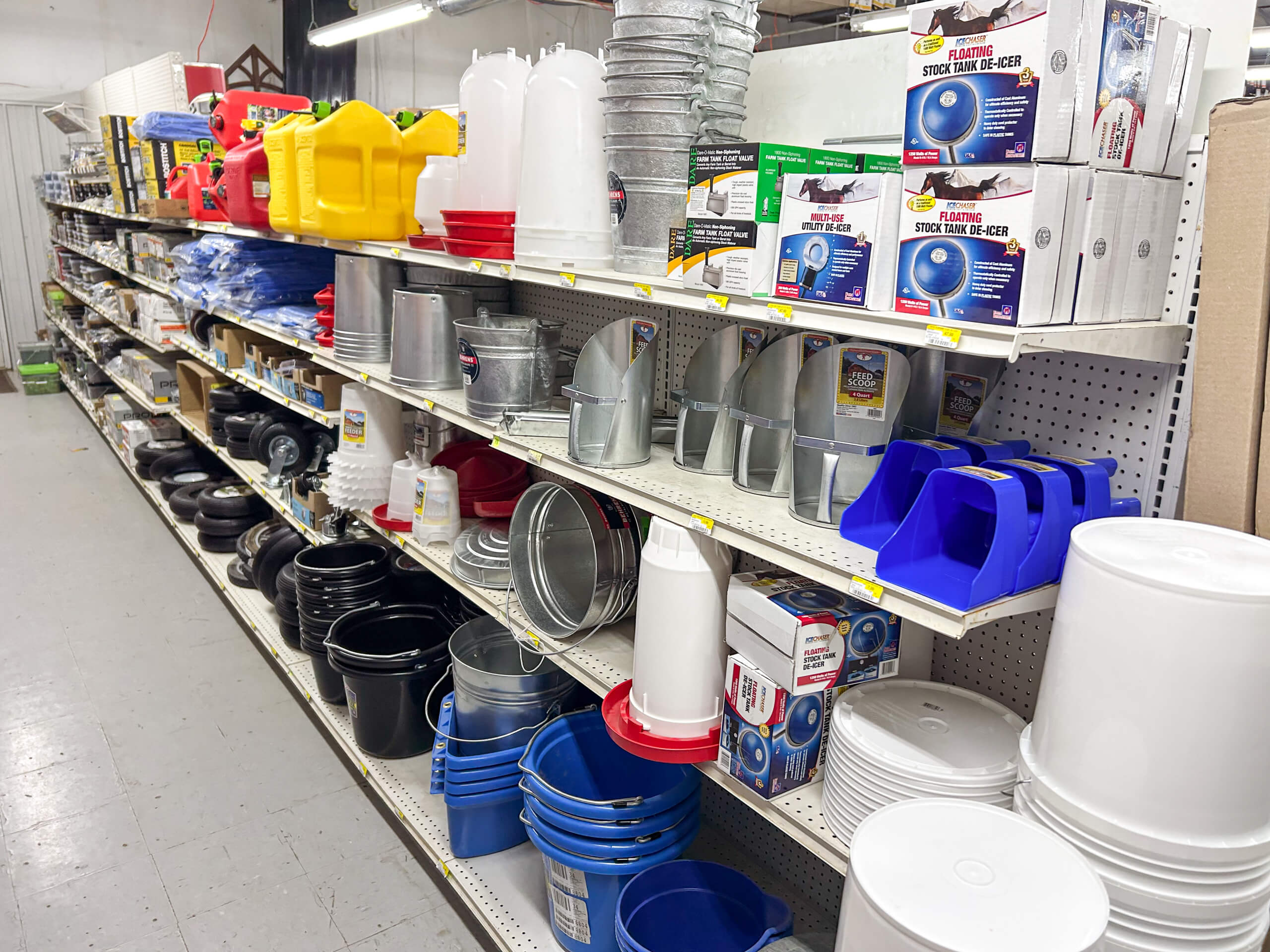 Benny's Hardware Barnett MO Shelves in a store display various farm and livestock supplies, including buckets, feeders, waterers, and ventilation ducts.