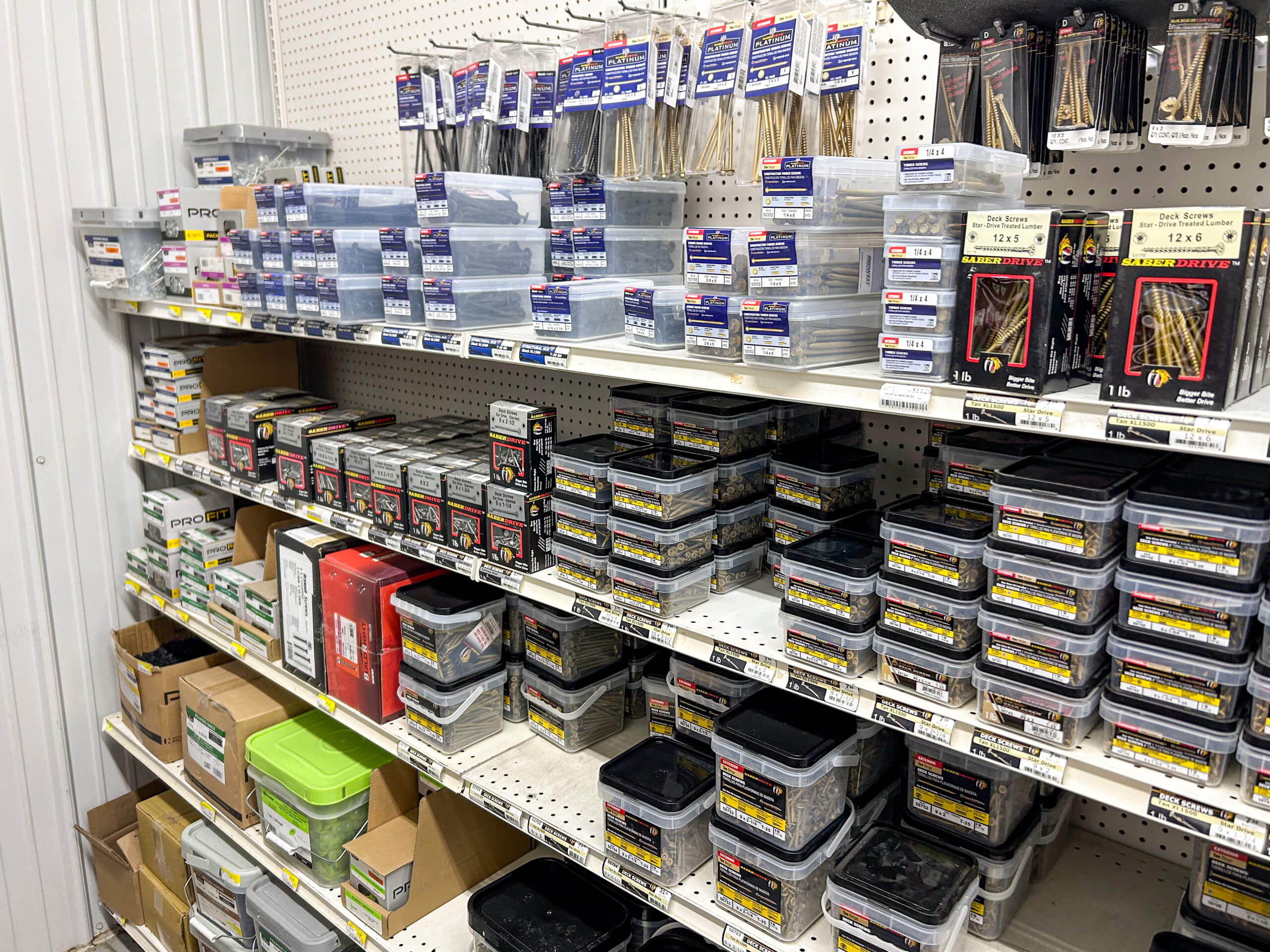 Benny's Hardware Barnett MO Shelves stocked with various sizes and brands of screws, nails, and fasteners in plastic containers and boxes at a hardware store.