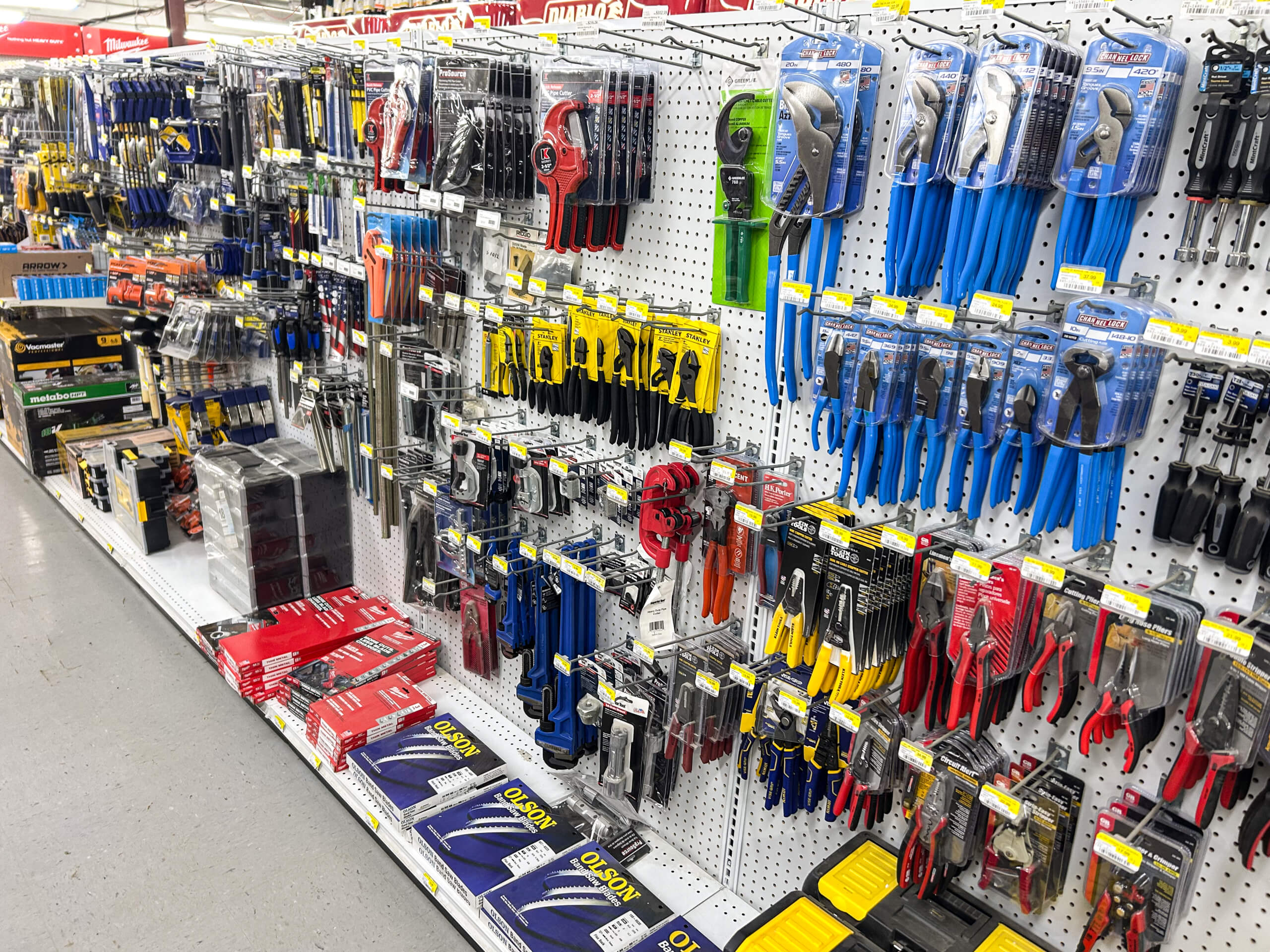 Benny's Hardware Barnett MO A store aisle displays various hand tools and pliers in blue, red, and yellow packaging hanging on hooks, with toolboxes and boxes stacked on the lower shelves.