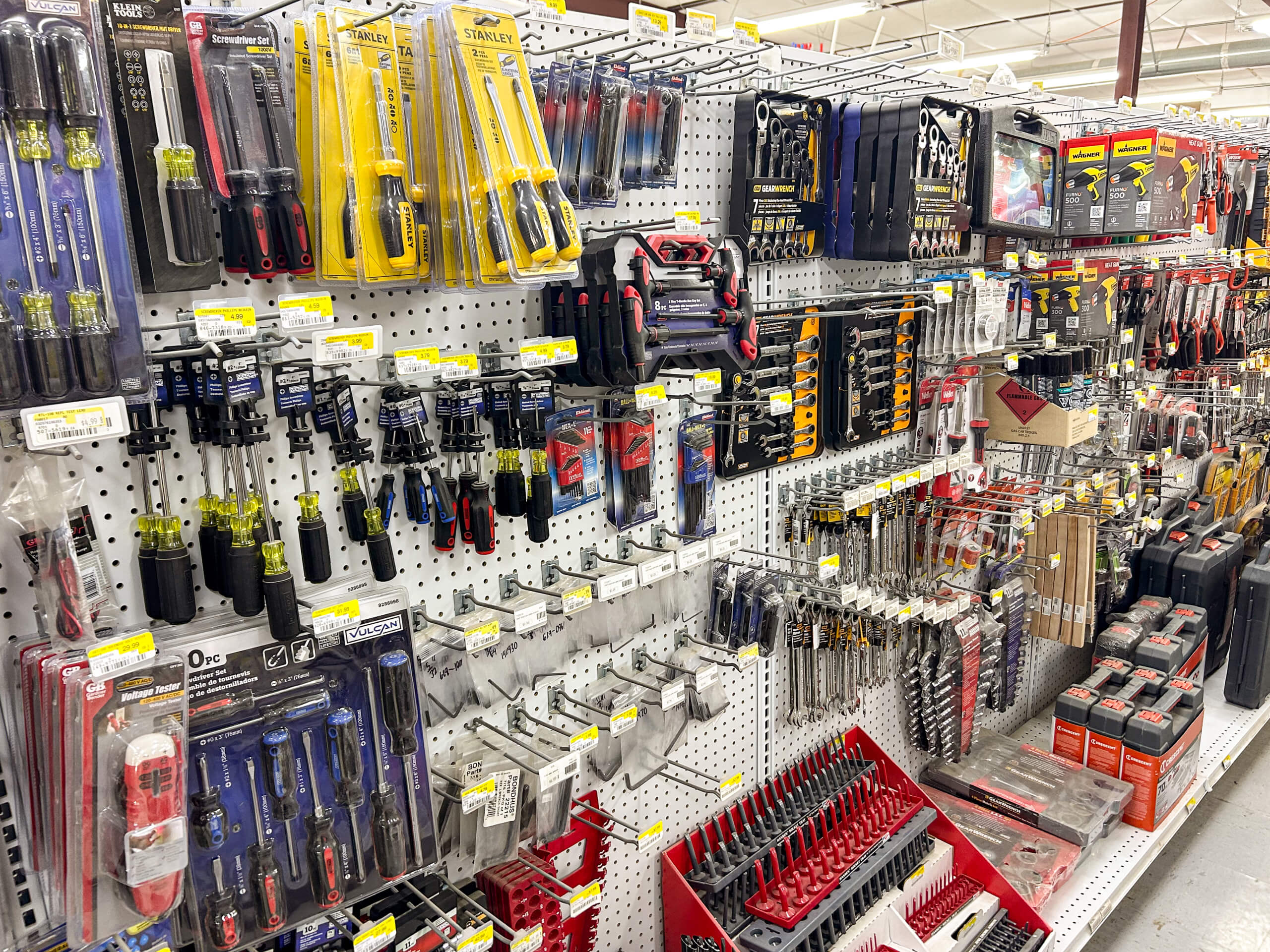 Benny's Hardware Barnett MO A hardware store aisle displays various hand tools, including screwdrivers, wrenches, pliers, drill bits, and tool sets arranged on shelves and hanging hooks.