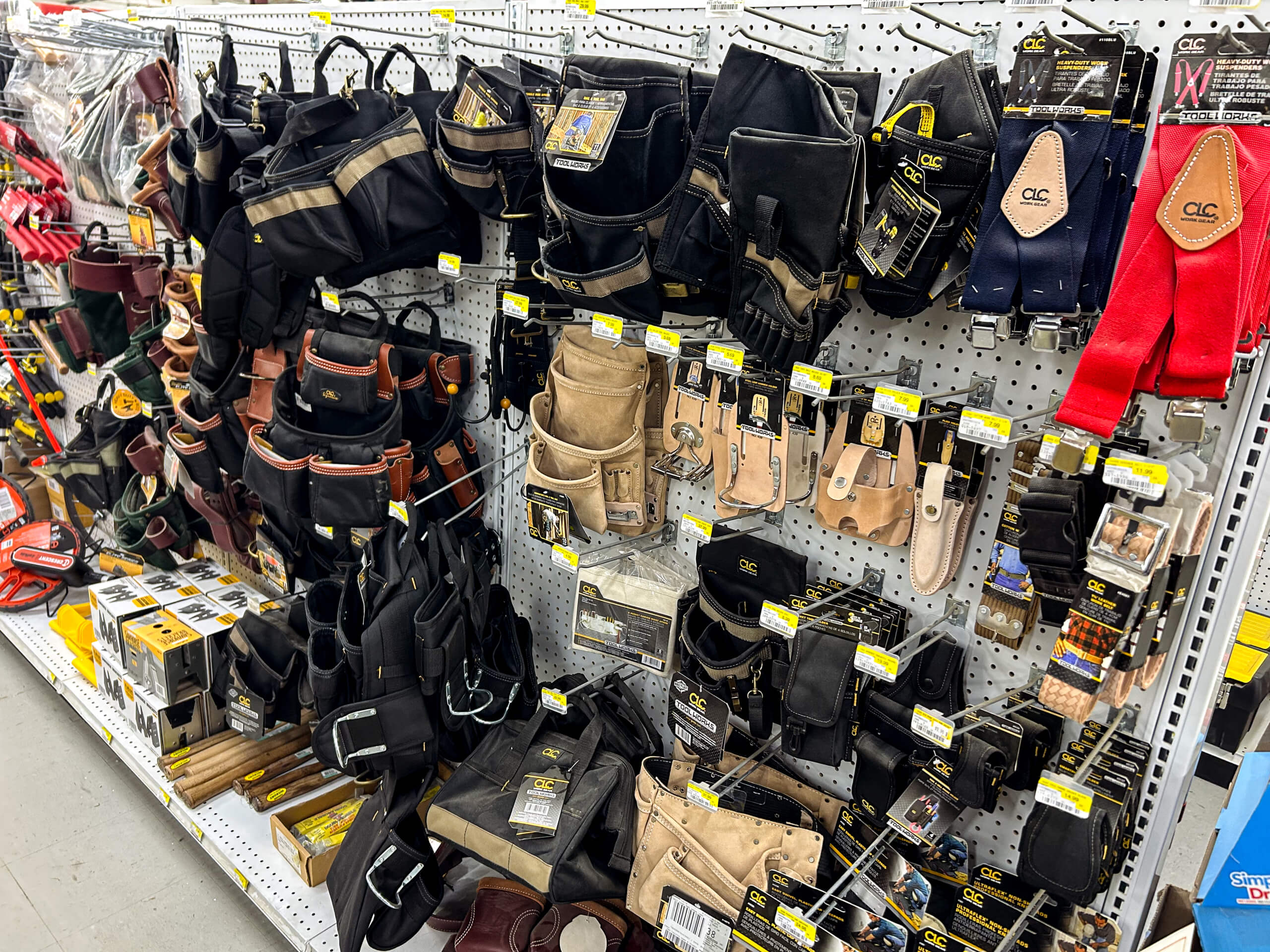Benny's Hardware Barnett MO Assorted tool belts, pouches, and holsters displayed on hooks and shelves in a hardware store aisle.
