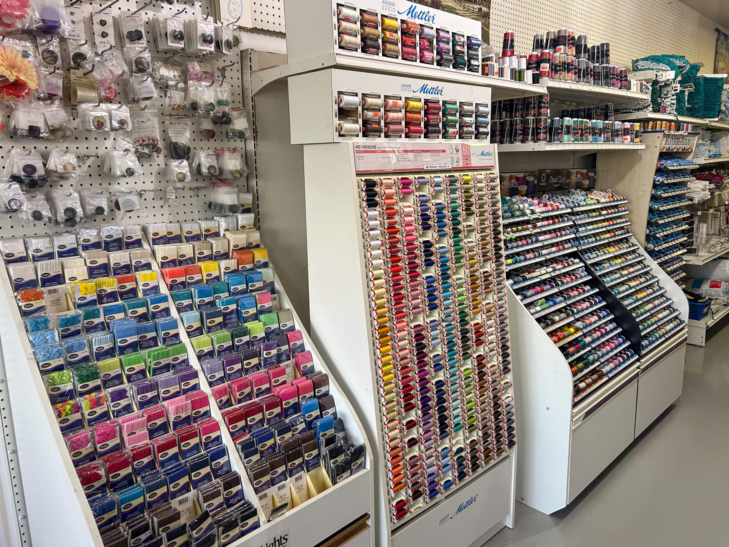 Miller's Country Store Grabill IN A store display with shelves filled with colorful thread spools and sewing supplies, including embroidery floss and various crafting accessories.