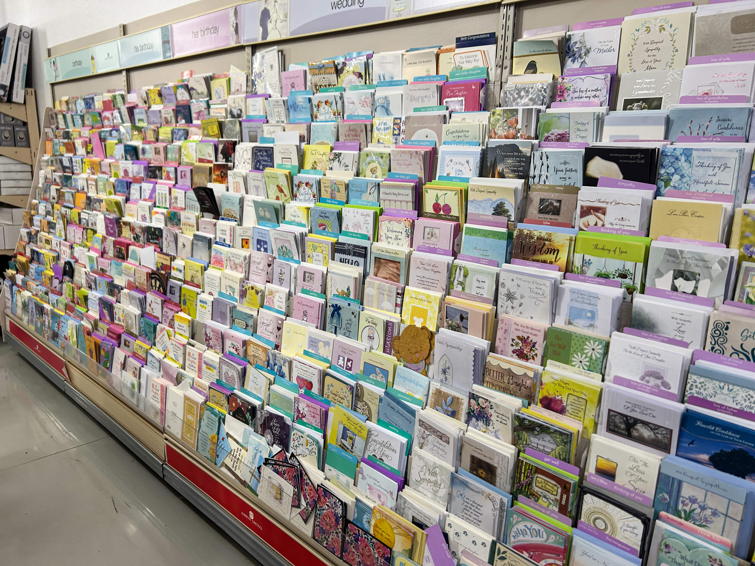 Miller's Country Store Grabill IN A store display of greeting cards organized in rows by occasion, with various colors and designs visible on the cards and shelves.