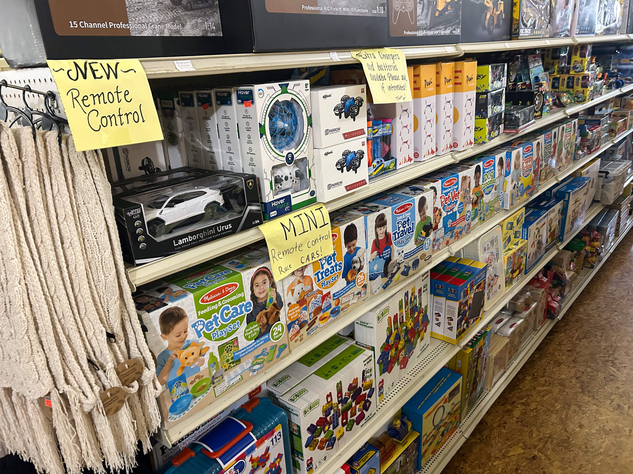 Miller's Country Store Grabill IN Store aisle shelves display various remote control toys, pet care playsets, building blocks, and children's activity kits, with handwritten signs noting new and mini remote control items.