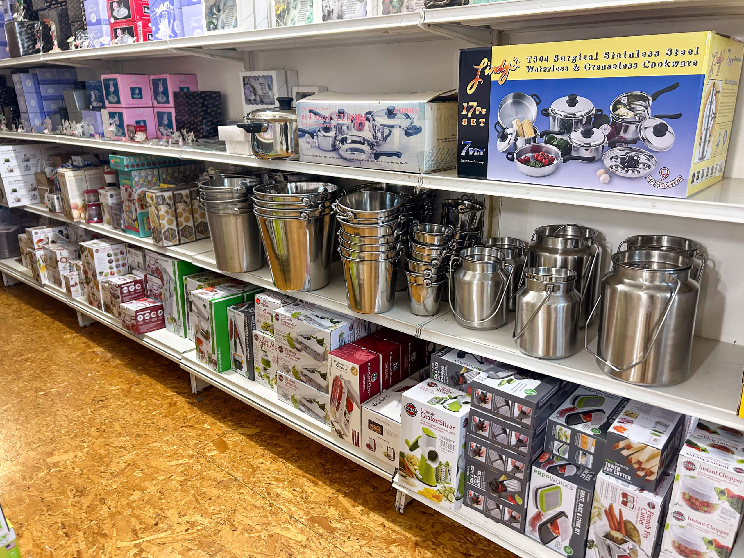 Miller's Country Store Grabill IN Kitchenware store shelves displaying stainless steel pots, buckets, and various boxed kitchen appliances and gadgets, all neatly arranged.