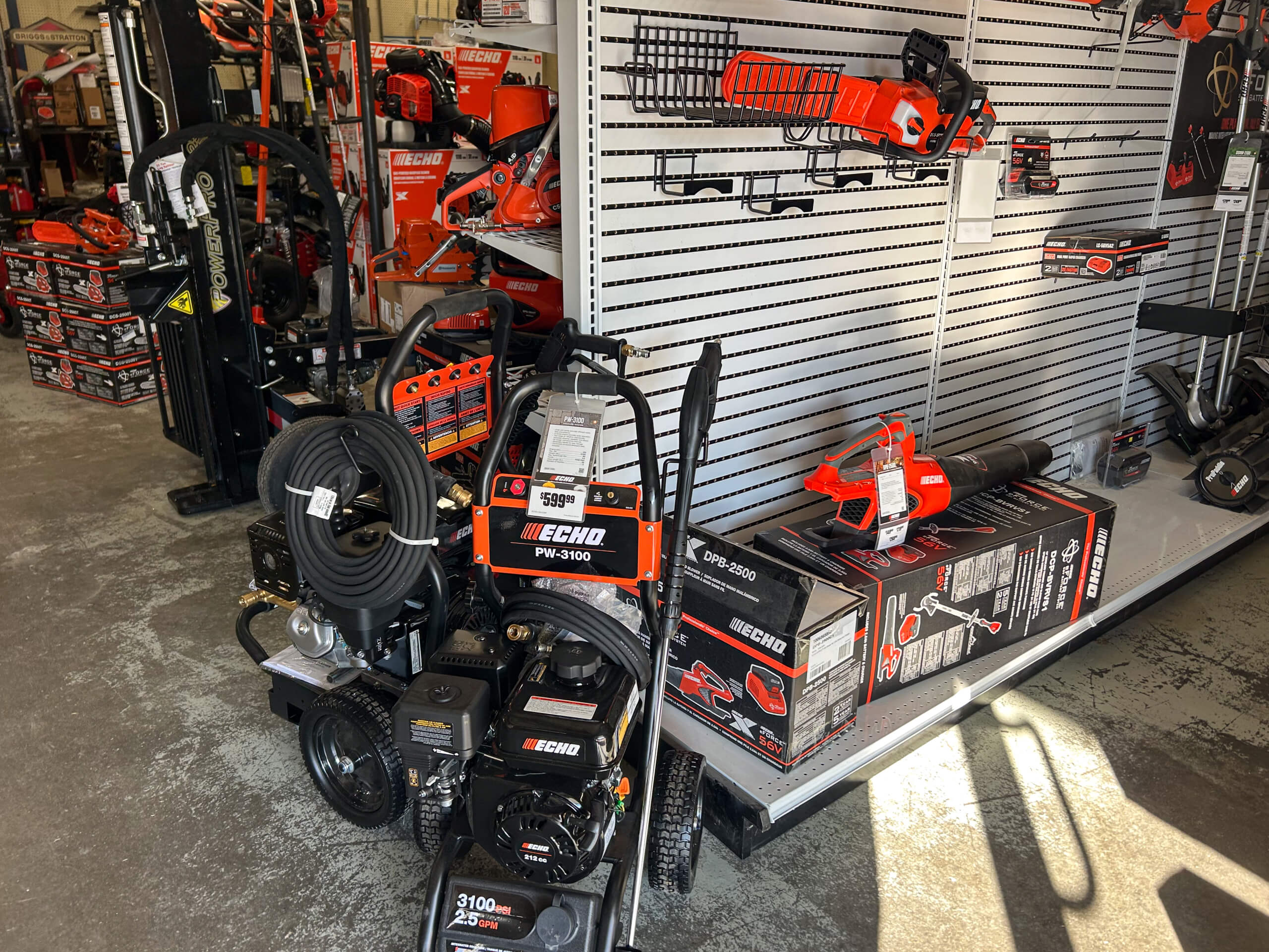 AK Small Engines Versailles, MO Power tools and equipment, including pressure washers and trimmers, displayed on shelves and the floor in a hardware store.